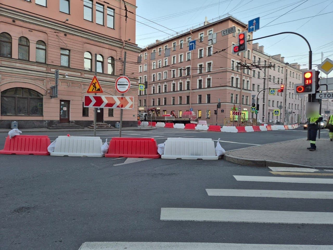 Полоса перед перекрёстком перекрыта водоналивными блоками, над ними знаки «Дорожные работы», «Опасность» и направляющий щит со стрелками